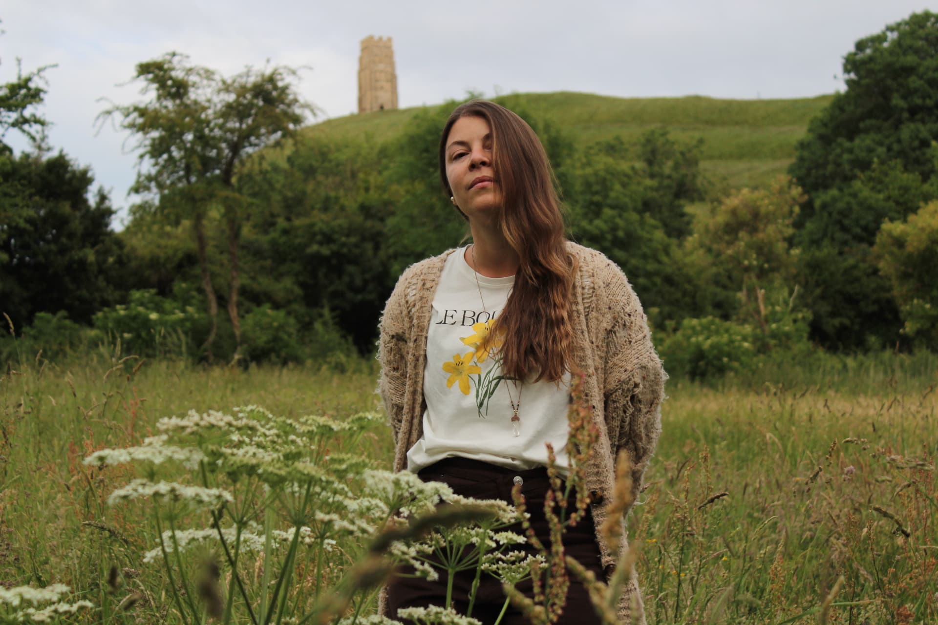 Ariela en un campo verde con una torre al fondo