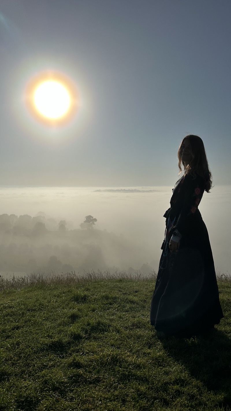 Ariela junto al sol sobre un paisaje de niebla y montaña